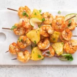 Grilled Chicked and Shrimp Skewers on a white cutting board on top of a white background.